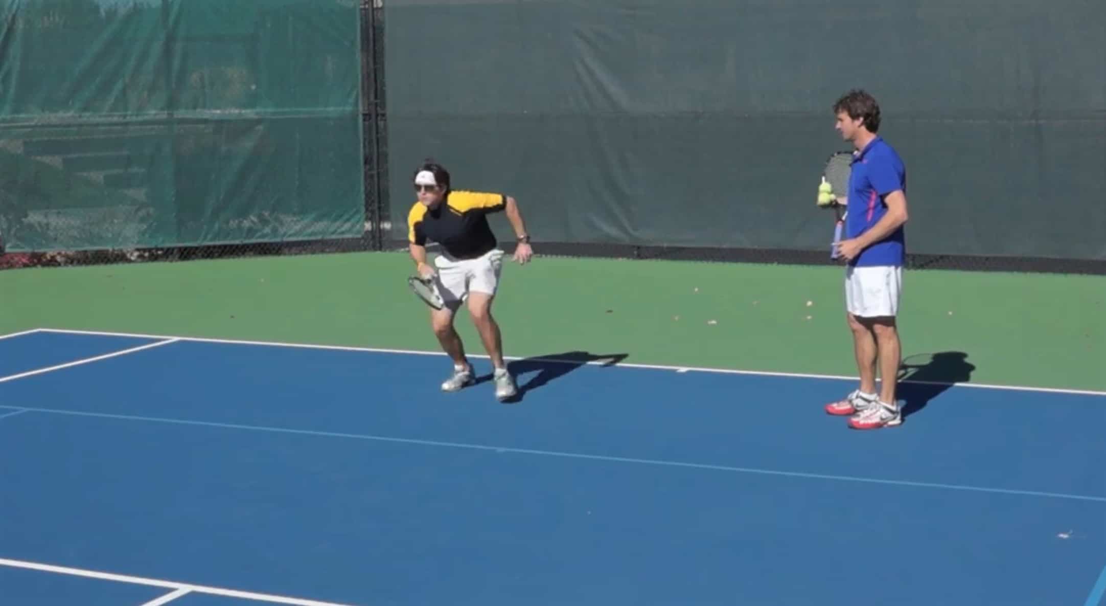 Jeff Salzenstein coaching a tennis player demonstrating serve and volley footwork.