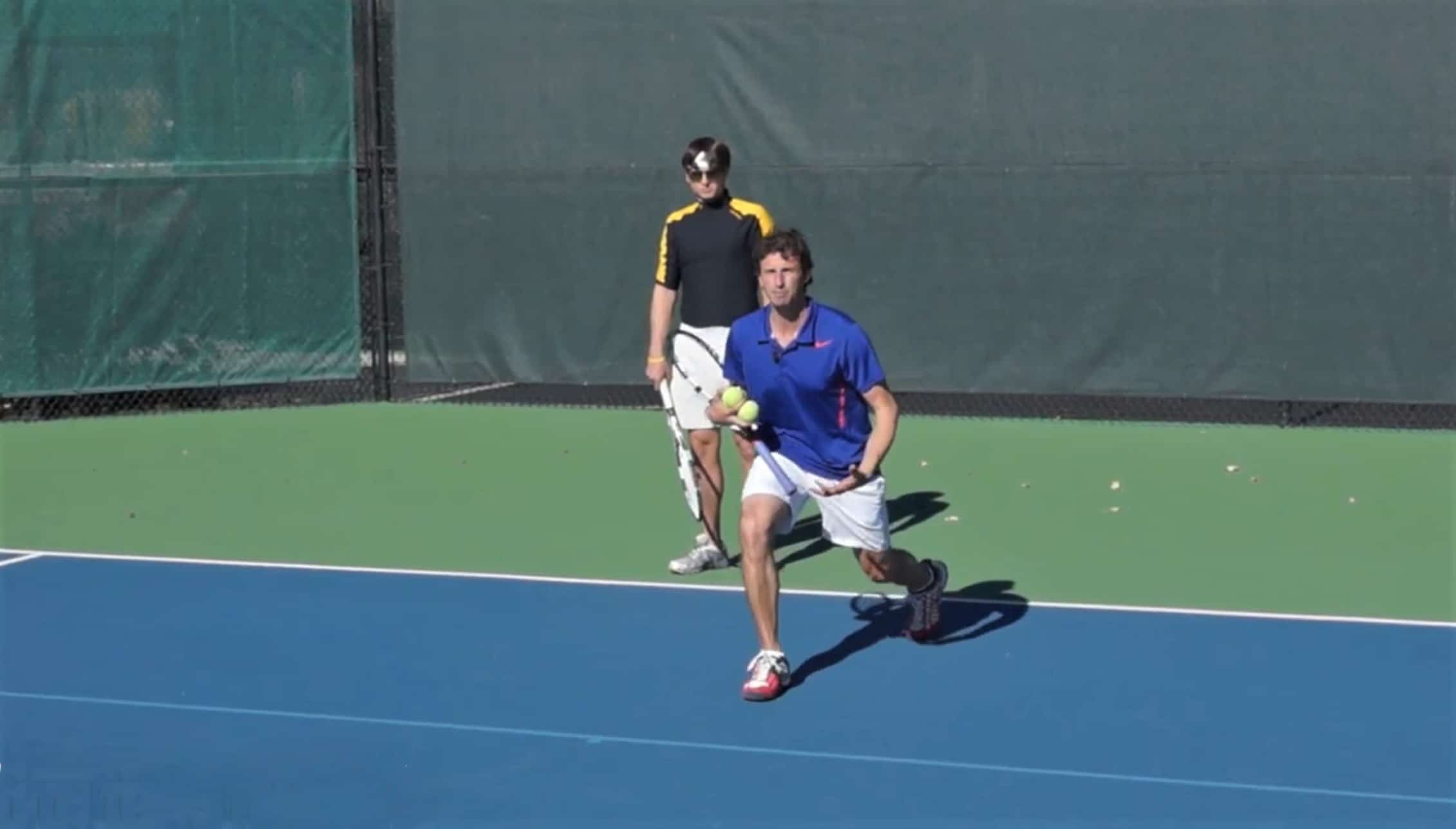 Jeff Salzenstein demonstrating a low lunge to a tennis player.