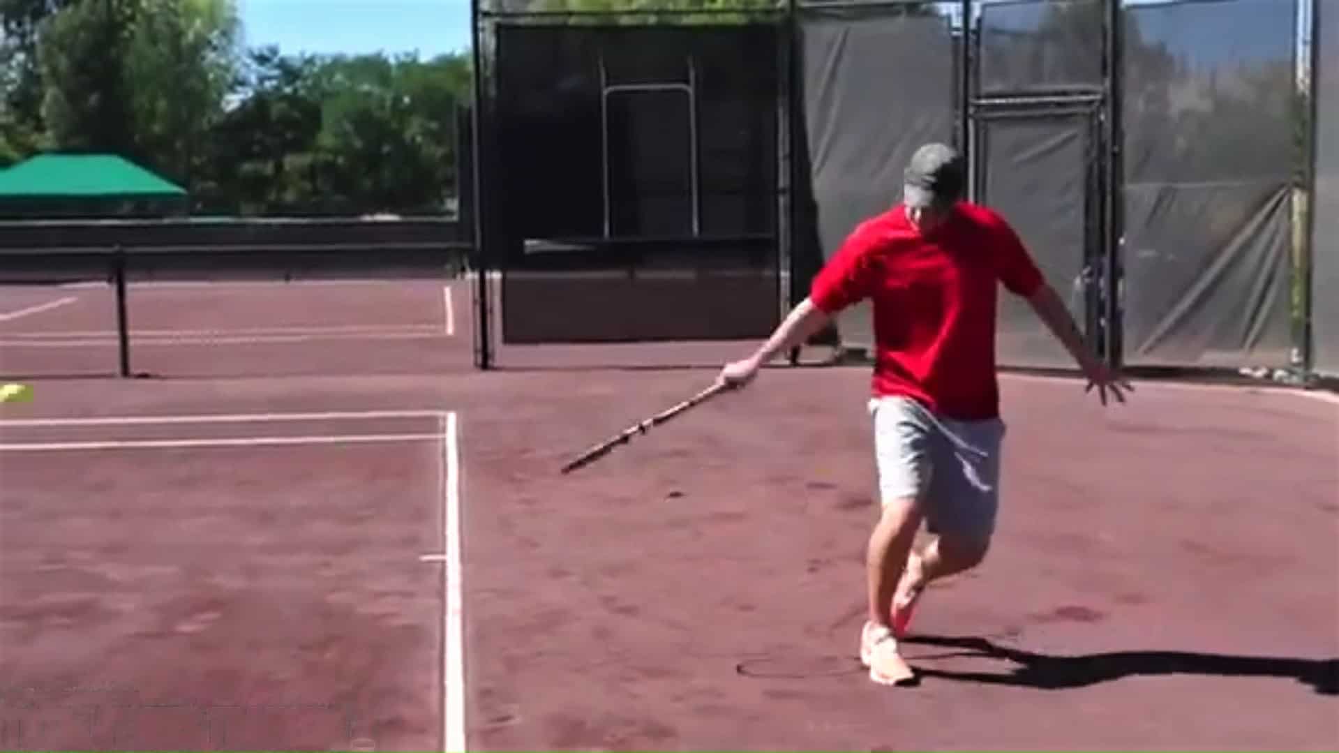 A tennis player demonstrating a one-handed tennis backhand slice follow through.